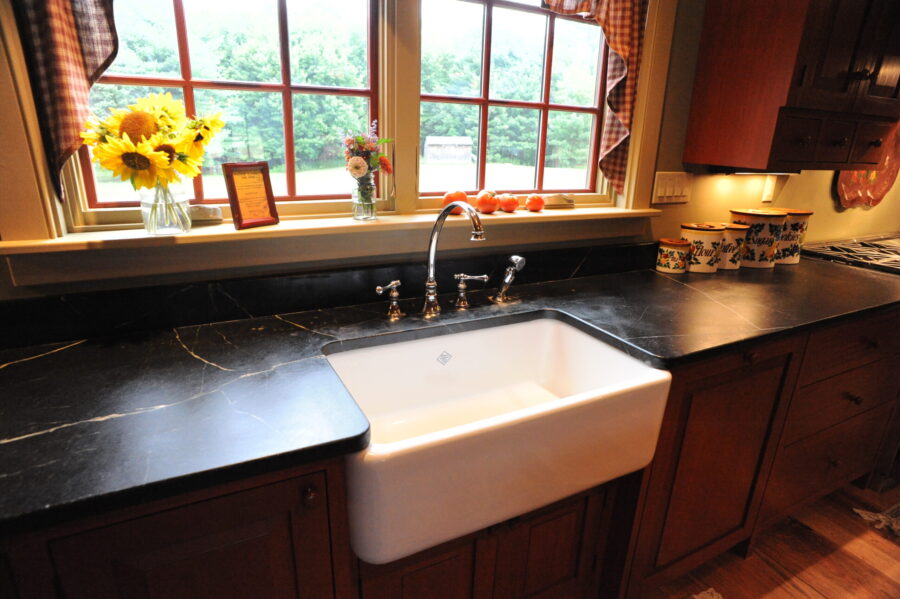 A deep white porcelin farmhouse sink inset in black soapstone counters.