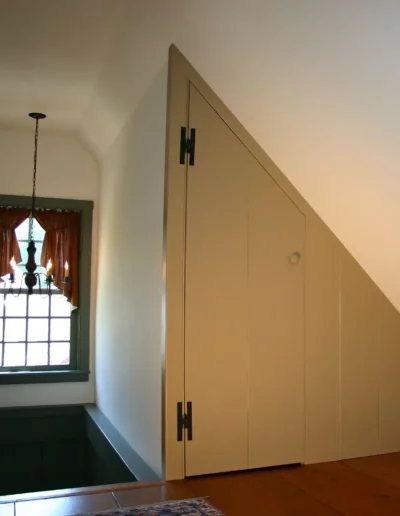 A second floor back hall angular closet beside a stairway in an Early New England home | Custom Built Ins