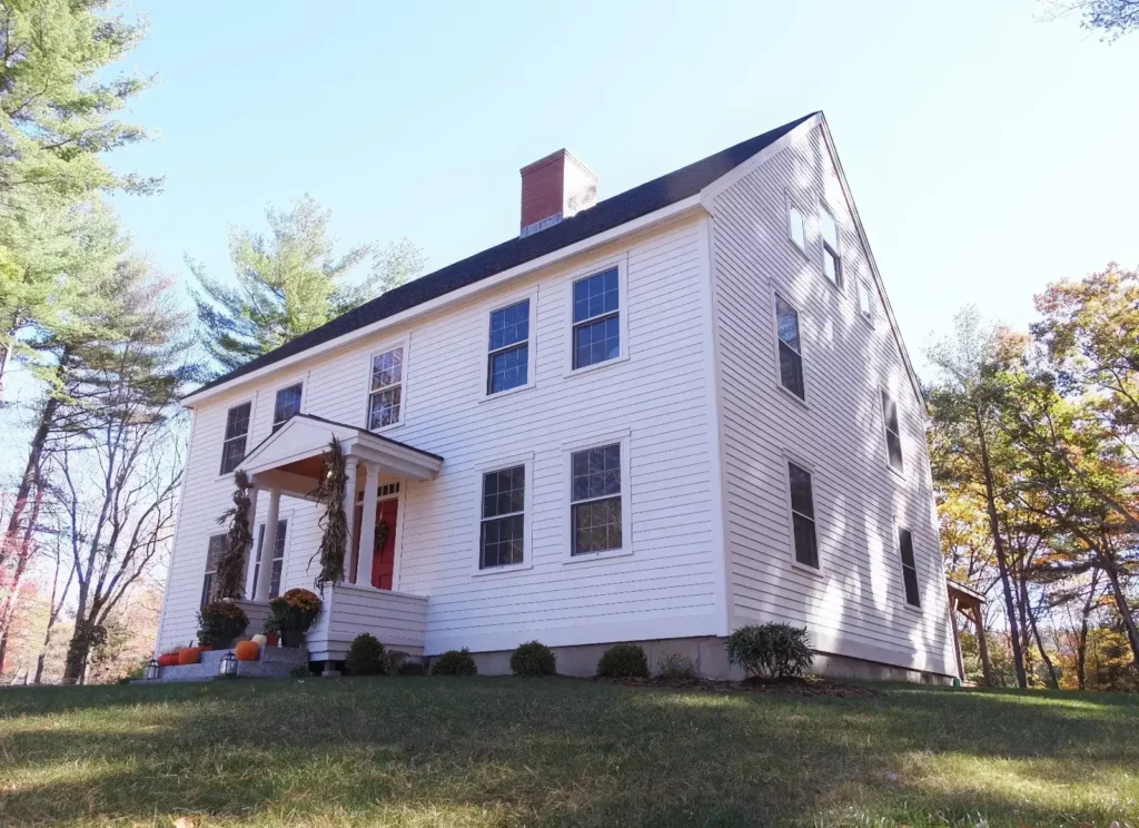Exterior photo of a white Colonial with a red front door from Early New England Homes